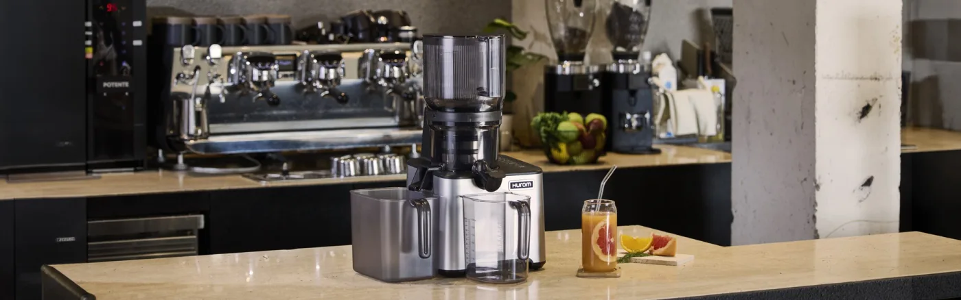 Hurom CP50 Commercial Slow Juicer im Thekenbereich neben Obst und Gläsern