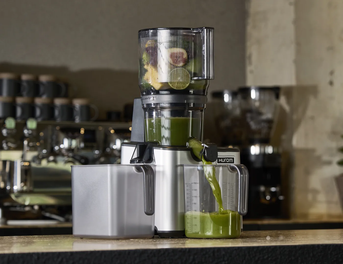 Hurom CP50 Commercial Slow Juicer auf der Theke einer Saftbar mit frisch gepresstem grünem Saft