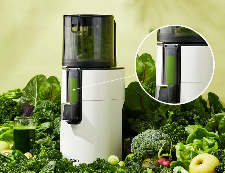 Hurom H400 Whole Slow Juicer umgeben von grünem Gemüse