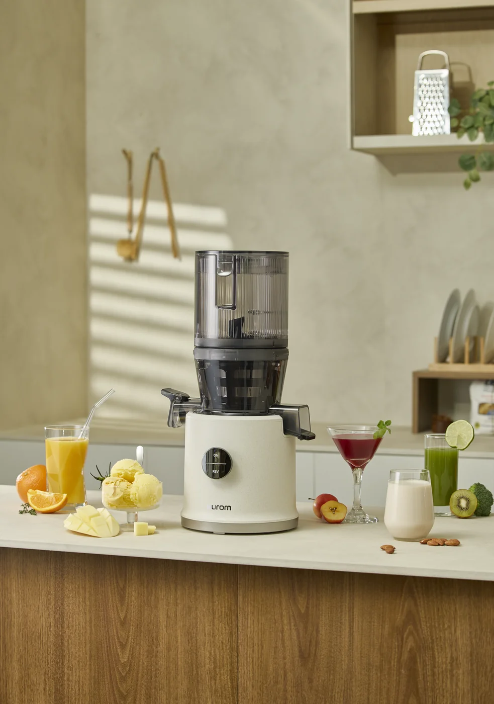 Mehrere frisch gepresste Säfte auf einer Küchentheke neben einem Hurom Slow Juicer